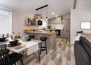 A modern kitchen with a central island, wooden cabinets, and pendant lighting. - Premium modern and contemporary luxury lodge perfect for a relaxing escape. (Workington)