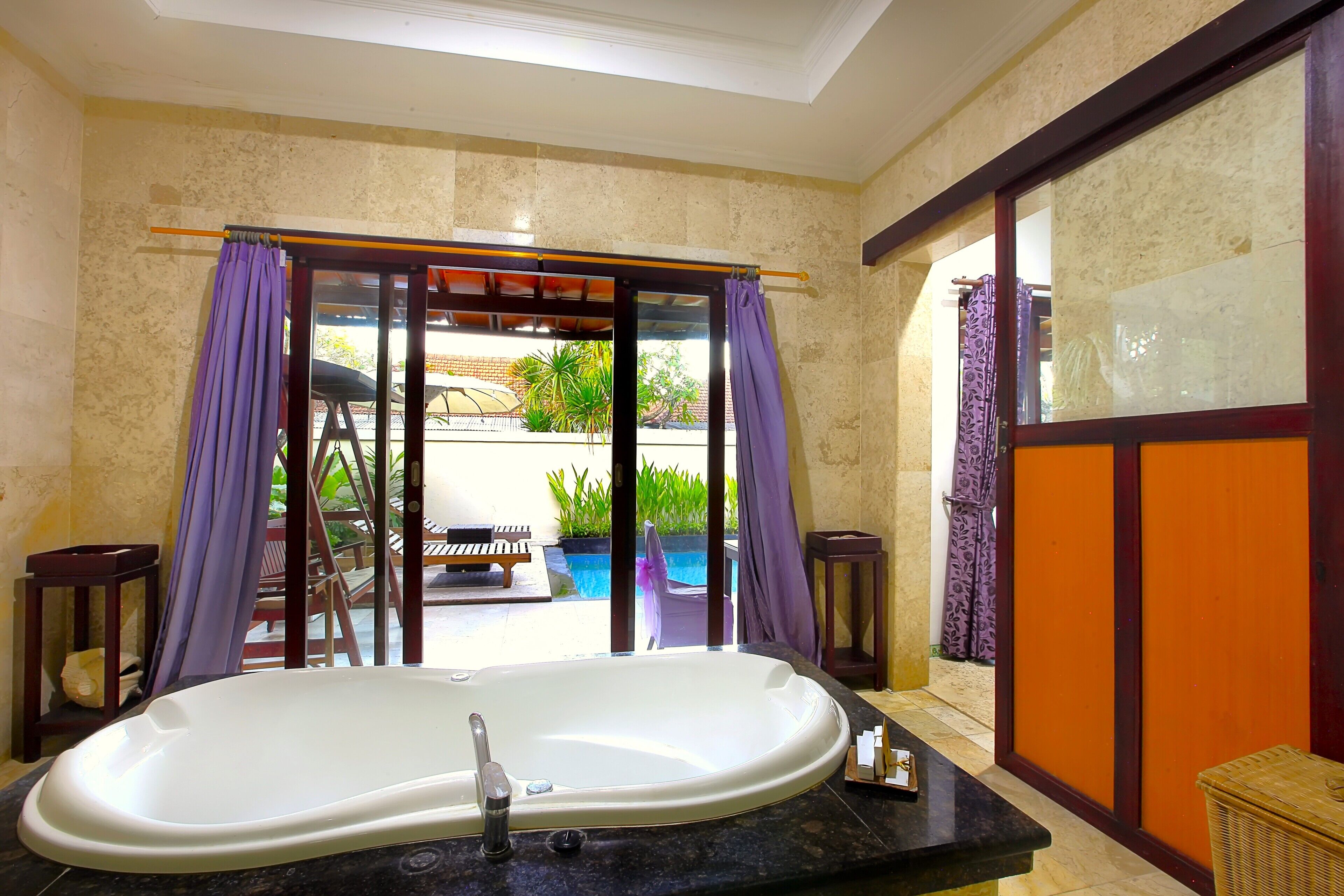 A bathroom with a bathtub, a shower, and a glass door leading to an outdoor area.