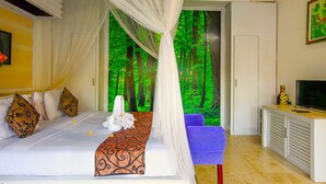 Un dormitorio con cama con dosel, televisión y baño visible a través de una puerta abierta.