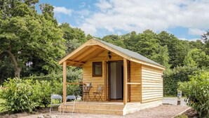 A small wooden cabin with a porch, a table, and chairs. - 1 bedroom accommodation in Oswestry (Oswestry)