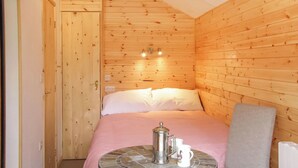 A wooden cabin room with a bed, a small table with a coffee pot, and a chair. - 1 bedroom accommodation in Oswestry (Oswestry)