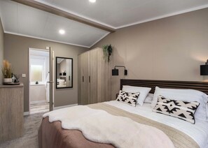 Une chambre à coucher avec un lit, une armoire, un miroir et une table de chevet.
