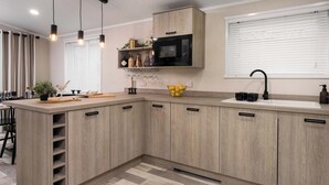 A modern kitchen with wooden cabinets, a microwave, a sink, and pendant lights.