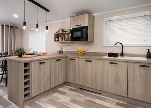 Une cuisine moderne avec des meubles en bois, un four à micro-ondes, un évier et des luminaires suspendus.