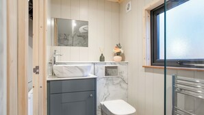 Ein kleines Badezimmer mit Marmorwaschbecken, Toilette, Spiegel und Fenster.