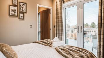 A bedroom with a bed, a view of the outside, and a door leading to another room.