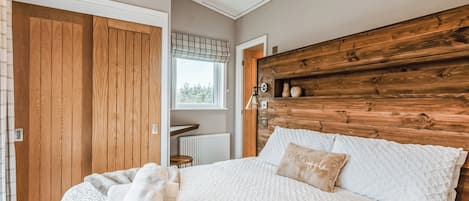 Un dormitorio con cabecera de madera, una cama grande con ropa de cama blanca, una ventana con persianas y un armario de madera.