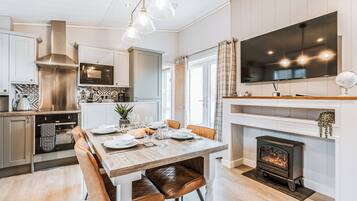 A modern kitchen with stainless steel appliances, a dining table set for six, and a fireplace.
