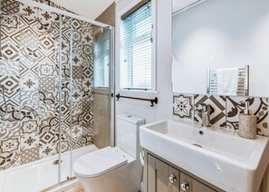 A bathroom with patterned tiles, a toilet, a sink, and a shower. - 2 bedroom accommodation in Bridgnorth (Bridgnorth)