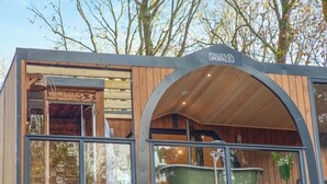 Una cabaña moderna con fachada de madera, ventanas amplias y un letrero que indica 'The Valley Pods'.