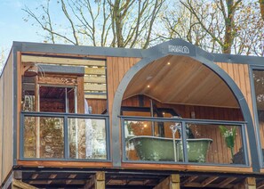 Uma cabana moderna com fachada de madeira, janelas grandes e uma placa indicando 'The Valley Pods'.