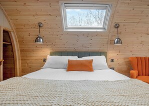 A room with a bed, a skylight, and two wall-mounted lamps.