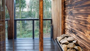 Una terraza de madera con un ventanal de vidrio que ofrece vistas a un bosque.
