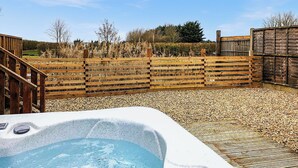 A hot tub in a wooden deck area with a wooden fence in the background.