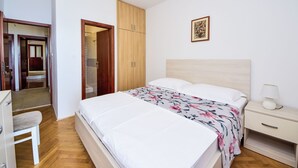 A bedroom with a bed, a nightstand, a chair, a wardrobe, and a door leading to a bathroom. - Apartment Lada by Interhome (Omiš)