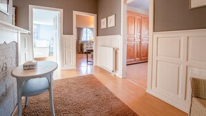 A spacious hallway with a wooden floor, white doors, and a chandelier. - Chante le Coq by Interhome (De Haan)