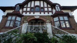 A two-story Tudor-style building with a prominent entrance, large windows, and a decorative archway. - Chante le Coq by Interhome (De Haan)