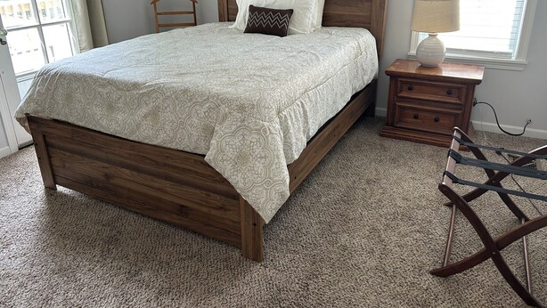 A bedroom with a wooden bed, a nightstand, a lamp, and a window with blinds. - 2-bedroom Century house in Cleveland with modern amenities (Cleveland)