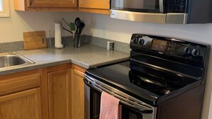 A kitchen with wooden cabinets, a stainless steel stove, a microwave, and a granite countertop. - 2-bedroom Century house in Cleveland with modern amenities (Cleveland)