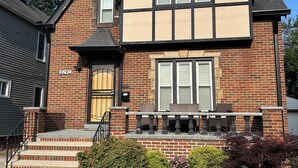 A two-story house with a brick facade, a gabled roof, and a front porch with a bench. - 2-bedroom Century house in Cleveland with modern amenities (Cleveland)