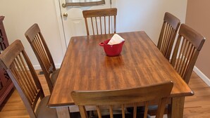 A wooden dining table with six chairs, a red bowl, and a window with blinds. - 2-bedroom Century house in Cleveland with modern amenities (Cleveland)