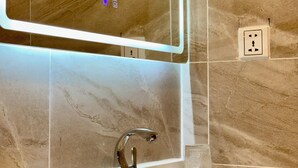 A modern bathroom with a large mirror, a sink, and a glass container on the countertop. - Keang You Boutique Hotel  (Phnom Penh)