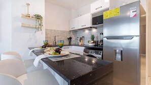 Eine moderne Küche mit schwarzer Arbeitsplatte, Edelstahlgeräten und einer weißen Spritzschutzwand.
