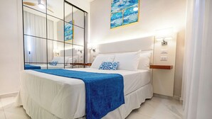 Ein Hotelzimmer mit einem großen Bett, einem Spiegel, einem Gemälde und einem Nachttisch mit einer Lampe.