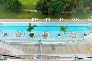 Piscina en la azotea con sillones de descanso y palmeras.