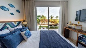Une chambre d’hôtel avec un lit, une télévision, un bureau avec une chaise et une vue sur une piscine et des palmiers.