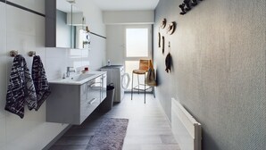 Un baño moderno con tocador blanco, un espejo grande y una lámpara colgante.