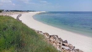 A sandy beach with a clear blue sea, a stone wall, and some greenery. - 50 m from the beach – House for 6 with garden (Treffiagat)