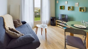 A modern living room with a sofa, TV, dining table, and a fireplace. - 100 m from the beach, 2 adults and 2 children (Fouesnant)