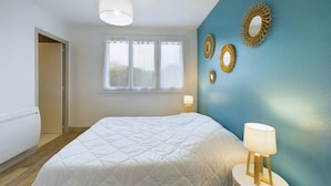 A bedroom with a large bed, a bedside table with a lamp, and decorative wall mirrors. - 100 m from the beach, 2 adults and 2 children (Fouesnant)