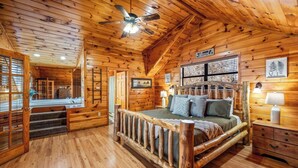 Ein Schlafzimmer in einer Blockhütte mit einem Bett, Holzwänden, einem Deckenventilator und einem Schild mit der Aufschrift 'Blessed'.