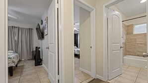 Una habitación de hotel con cama, televisión, ducha y baño.