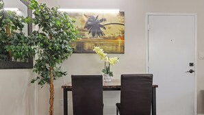 Comedor con dos sillas, una mesa, una planta en maceta y un cuadro colgado en la pared.