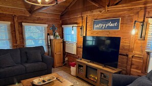 Una habitación acogedora de estilo cabaña con un televisor grande, muebles de madera y una chimenea.