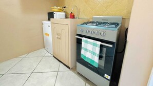 Una cocina funcional con estufa a gas, microondas y refrigerador.
