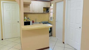 Una cocina compacta con armarios blancos, una pequeña encimera y un lavabo.