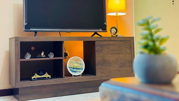 Un televisor sobre un soporte de madera, con una lámpara y adornos.