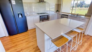 Una cocina moderna con una isla central, electrodomésticos de acero inoxidable y vistas al exterior.