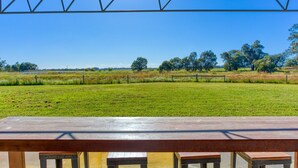Una mesa de picnic con bancos en un campo cubierto de césped, con árboles al fondo.