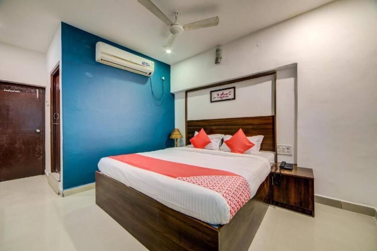 Un dormitorio con una cama, ventilador de techo, aire acondicionado y una mesita de noche con teléfono.