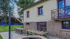 A patio with outdoor seating, a fire pit, and a stone building with purple windows.