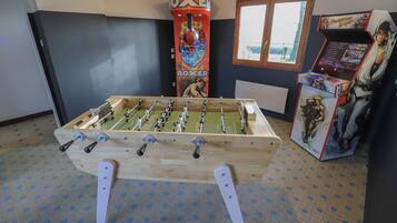 Ein Kicker steht in einem Raum mit Fenster und Spielautomaten.