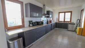 A modern kitchen with grey cabinets, stainless steel appliances, and a large window providing natural light.