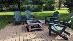 A wooden deck with Adirondack chairs and a square fire pit. - Cozy Lake view 3-bedroom house WiFi, AC in Oshkosh-Great spaces inside & out EAA (Oshkosh)