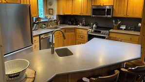 A modern kitchen with wooden cabinets, stainless steel appliances, and a central island. - Cozy Lake view 3-bedroom house WiFi, AC in Oshkosh-Great spaces inside & out EAA (Oshkosh)