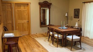 A dining area with a wooden table, chairs, a mirror, and a rug. - Cozy Lake view 3-bedroom house WiFi, AC in Oshkosh-Great spaces inside & out EAA (Oshkosh)